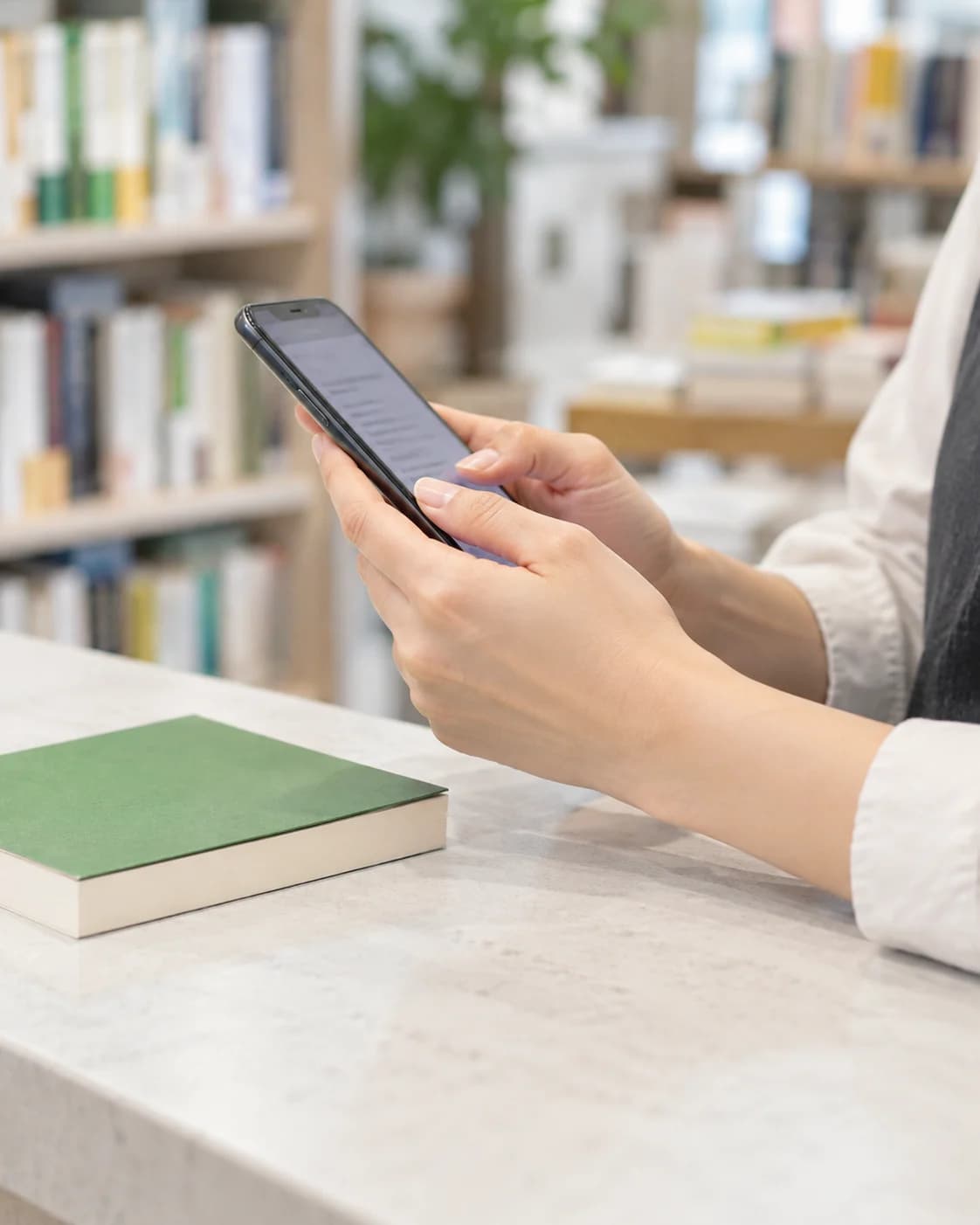 書店のカウンターでスマホを使って本を読む様子のイメージ